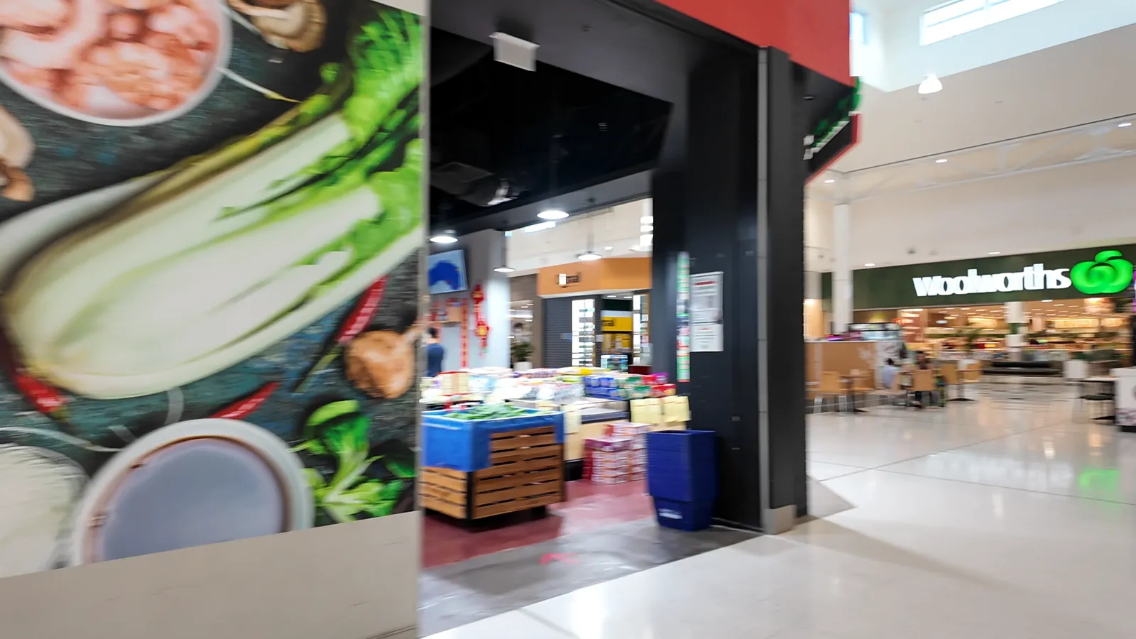 A supermarket entrance inside a shopping centre, with fresh produce on display
