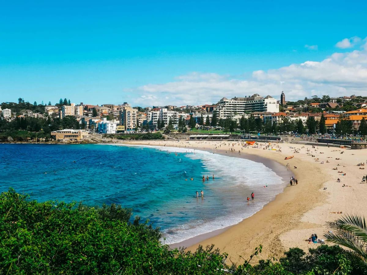 The crescent of Coogee Beach seen from the headland, with the dense apartment blocks and houses of the suburb stacked behind the promenade