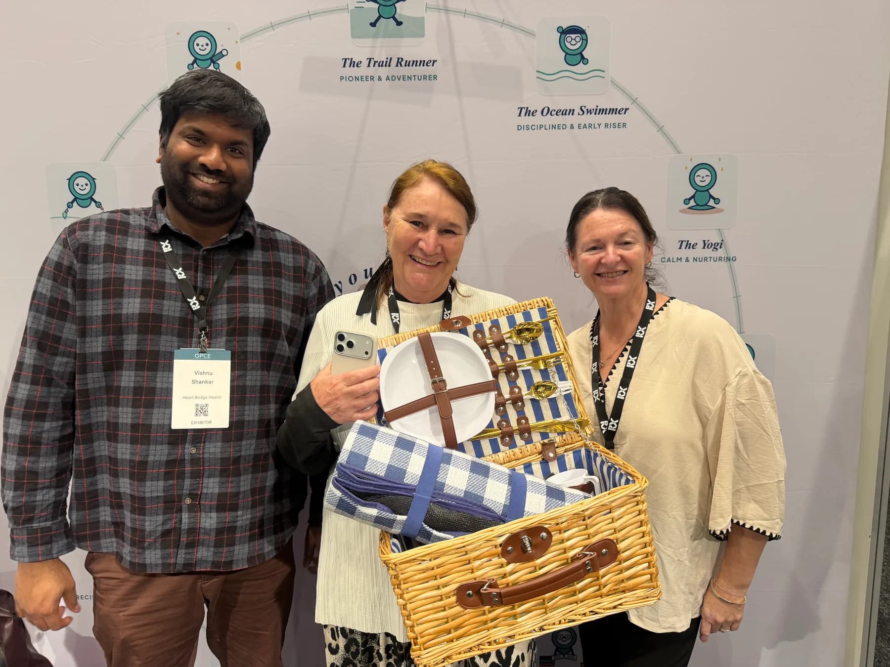 The Heart Bridge Health team at the GPCE stand, handing over the picnic hamper prize