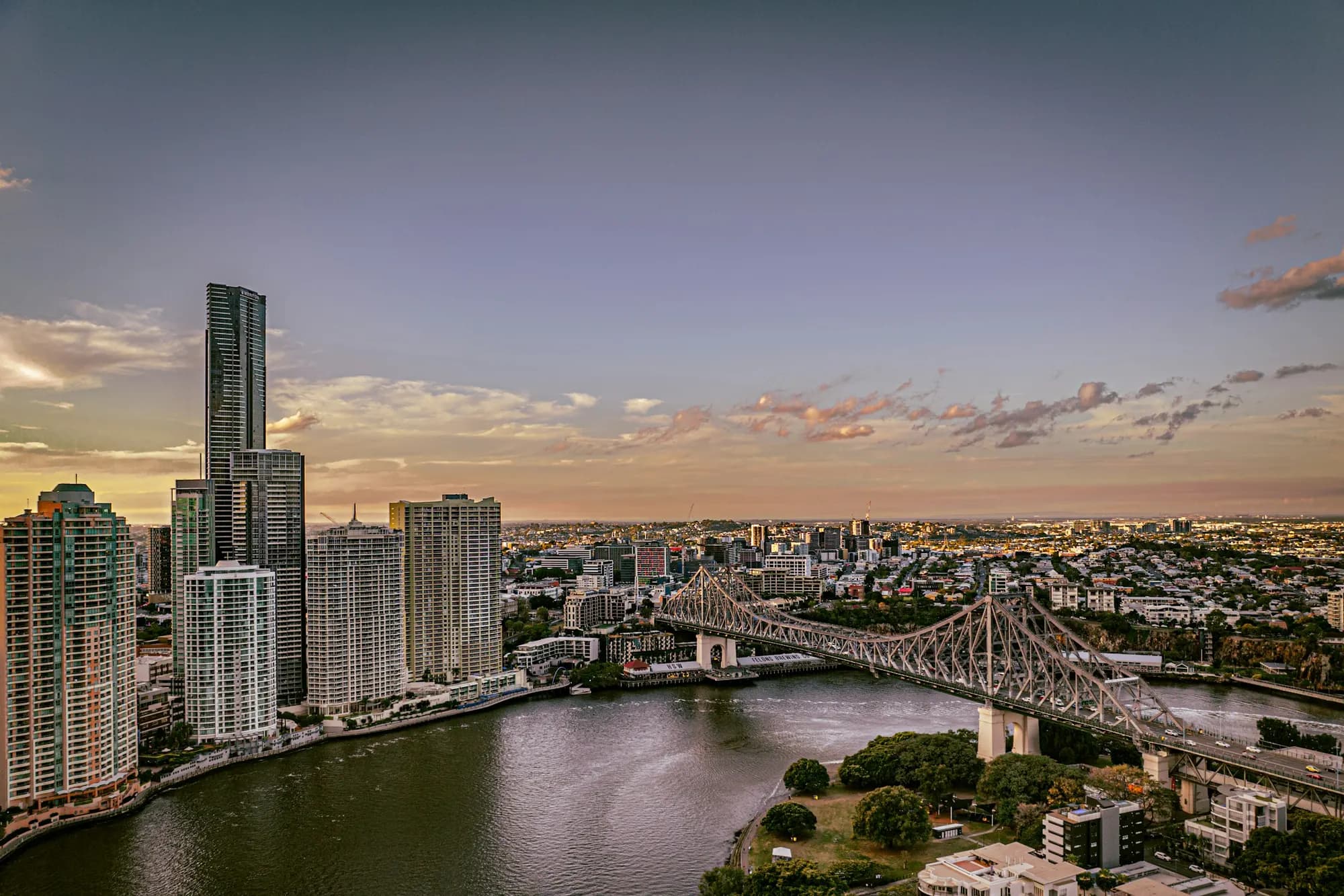 A wide view of the Brisbane River at dusk, the CBD towers on the left and the Story Bridge reaching across to the inner east