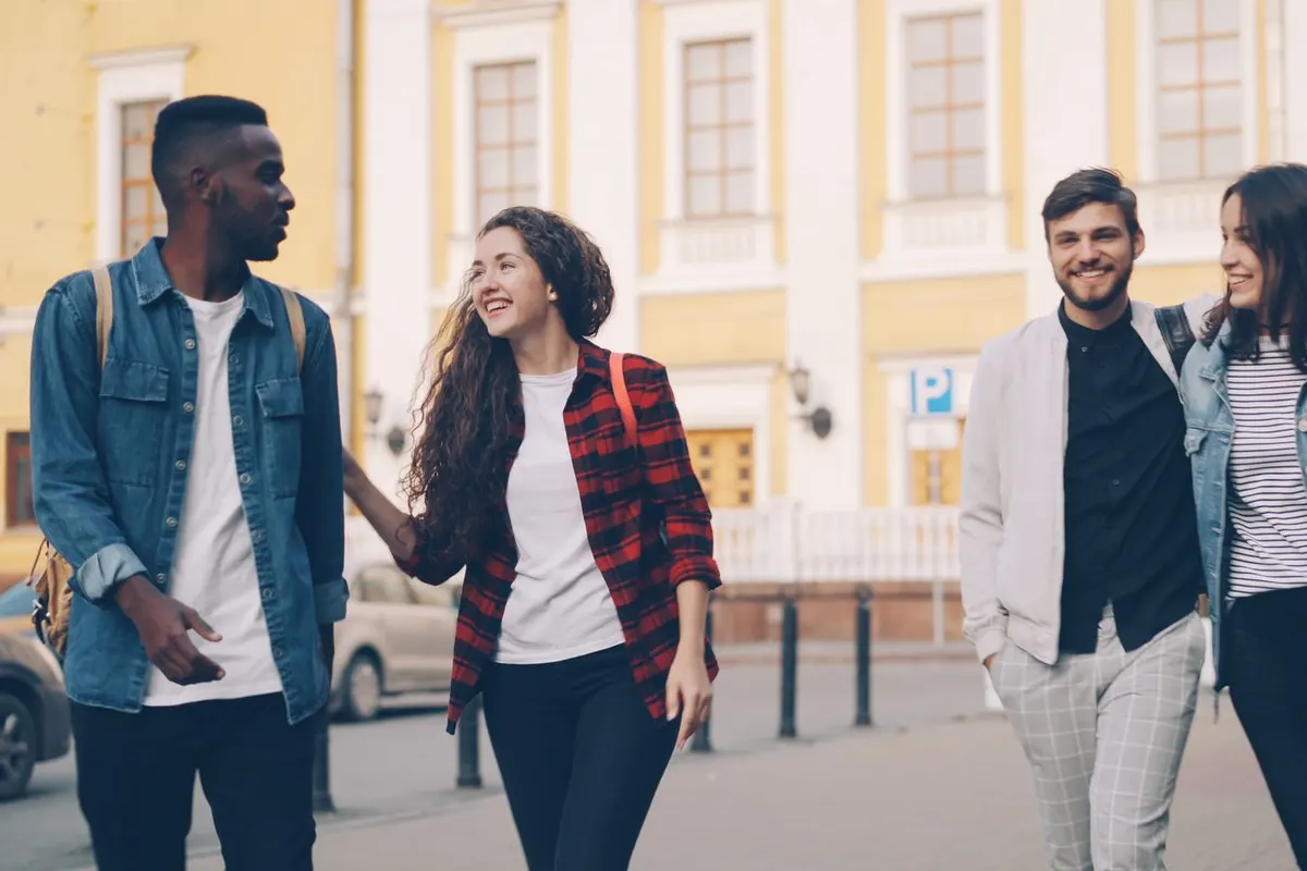 Three adults walking and talking together on a city street on a bright day