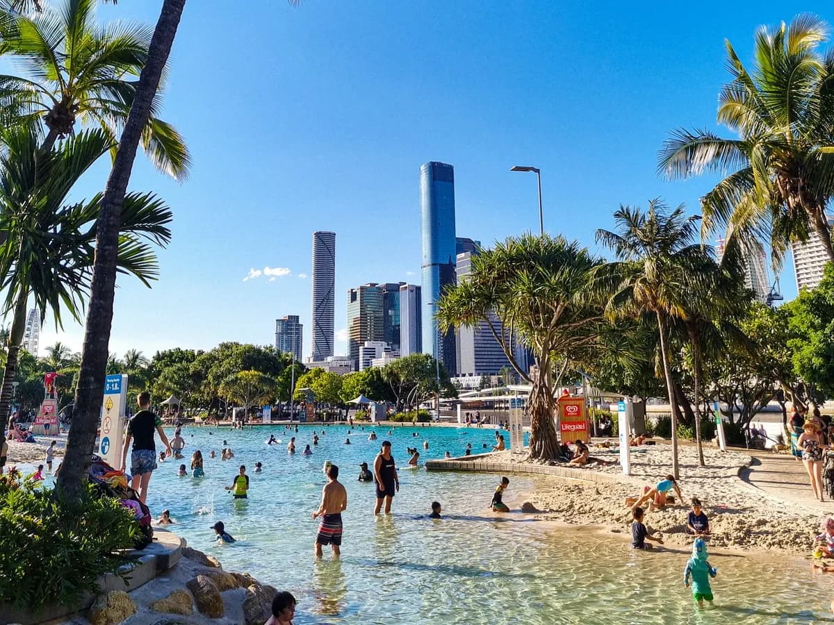 Streets Beach at South Bank, Brisbane — a man-made lagoon fringed with palms and sand, with the city towers rising behind it