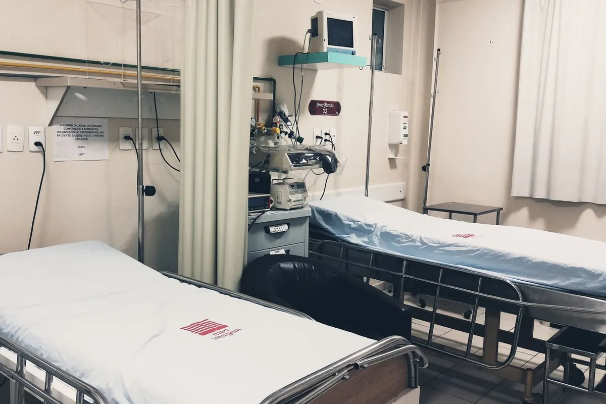 An empty, clean hospital ward with made-up beds and monitoring equipment